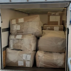 Commercial transport truck cargo bay tightly packed with shrink-wrapped packages and cardboard shipping crates